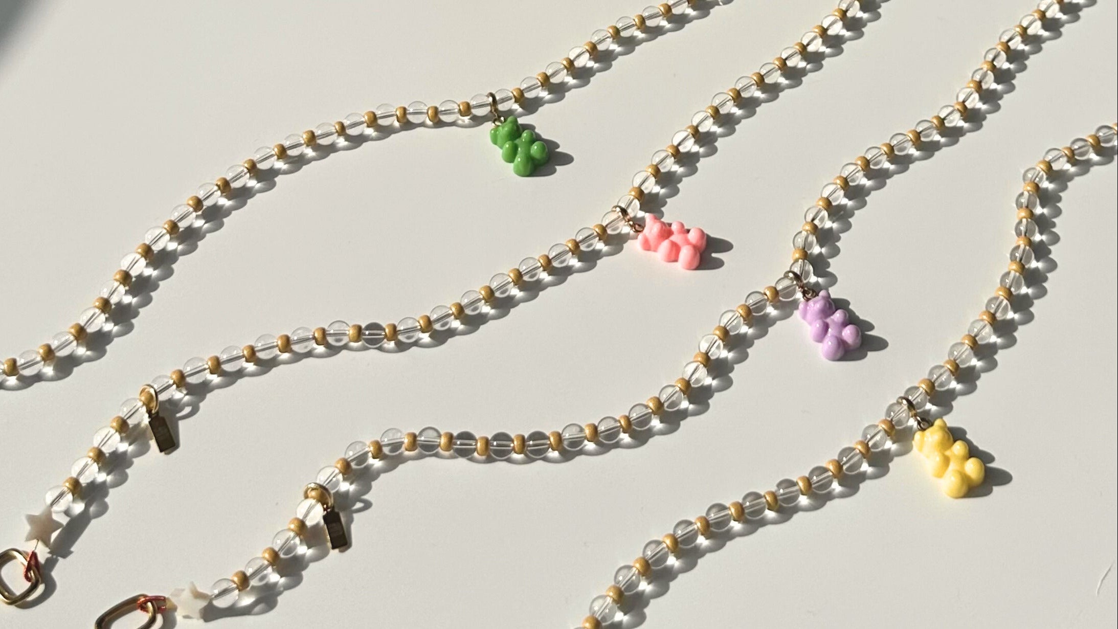 Three beaded chains with colorful charms on a light gray background