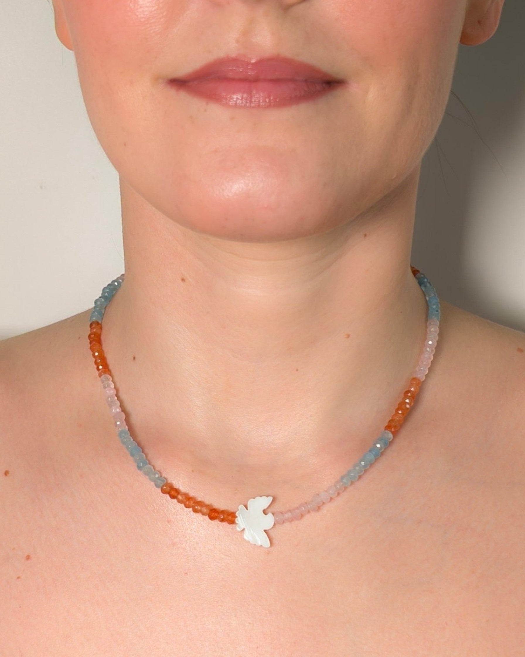 Necklace with a bird pendant worn by a person against a neutral background